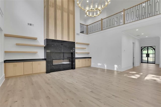 3903 Indian Shoals Rd SE, Bethlehem, GA 30620 - unfurnished living room featuring a towering ceiling, light wood finished floors, a chandelier, a tiled fireplace, and recessed lighting