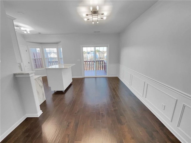 unfurnished dining area featuring visible vents, dark wood finished floors, and a decorative wall