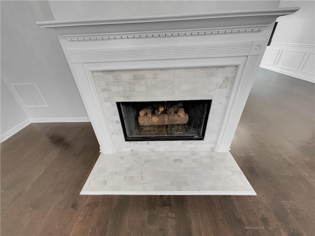 room details with a fireplace with flush hearth, visible vents, a decorative wall, and wood finished floors