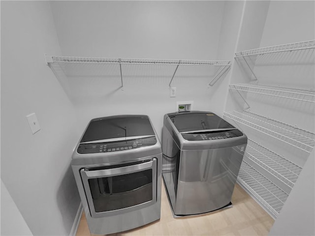 laundry area with laundry area, washing machine and clothes dryer, and wood finished floors