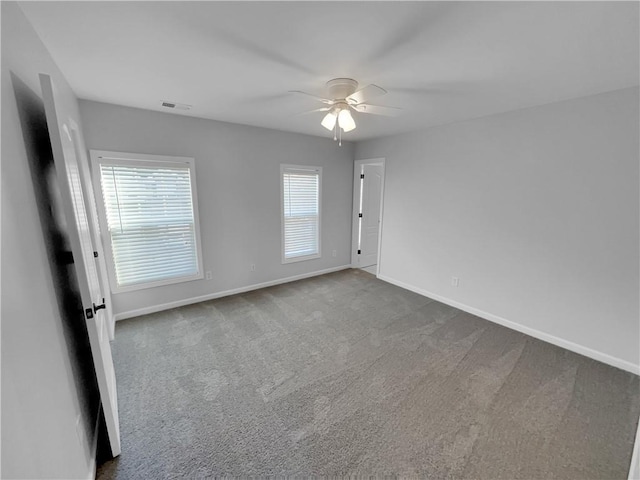 carpeted empty room featuring a ceiling fan, visible vents, and baseboards