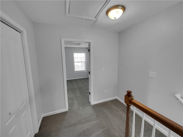 hall with carpet floors, visible vents, attic access, an upstairs landing, and baseboards