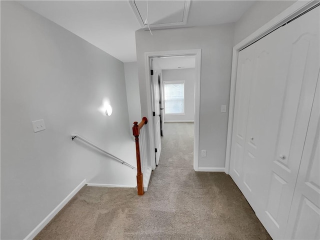 hallway featuring attic access, carpet, an upstairs landing, and baseboards