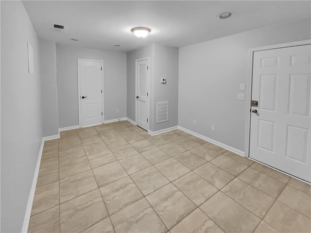 empty room featuring light tile patterned floors, visible vents, and baseboards