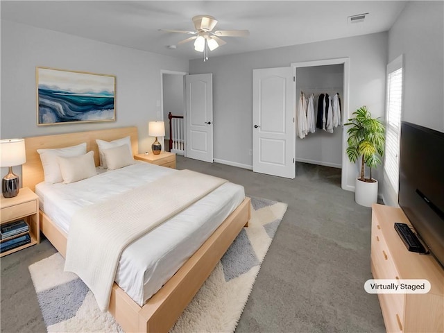 carpeted bedroom with a closet, visible vents, a spacious closet, ceiling fan, and baseboards