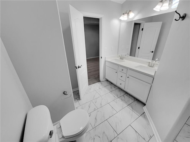 full bath featuring marble finish floor, double vanity, a sink, and toilet