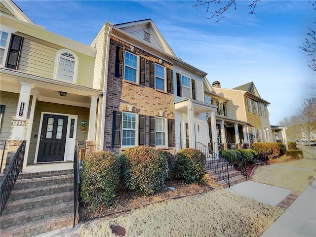 townhome / multi-family property featuring a residential view, a porch, and brick siding