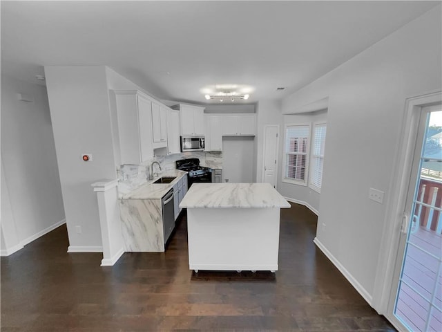 kitchen featuring a sink, appliances with stainless steel finishes, backsplash, light stone countertops, and dark wood finished floors