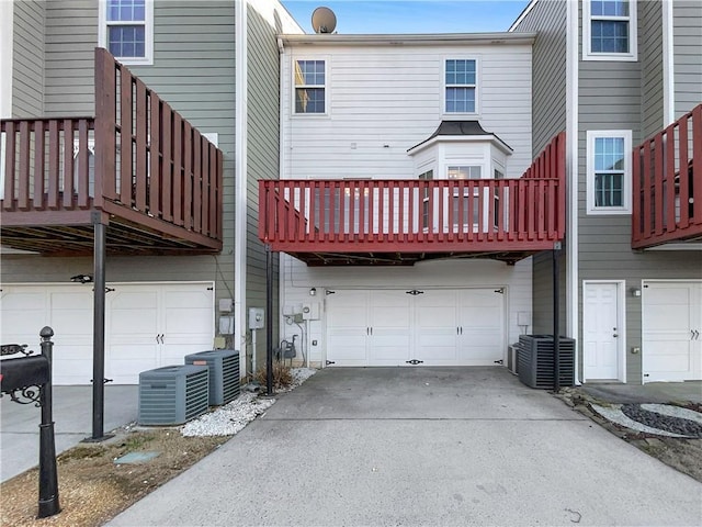 back of property with central AC, an attached garage, and driveway