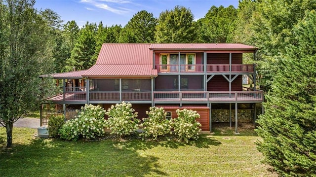 back of property featuring a sunroom and a lawn