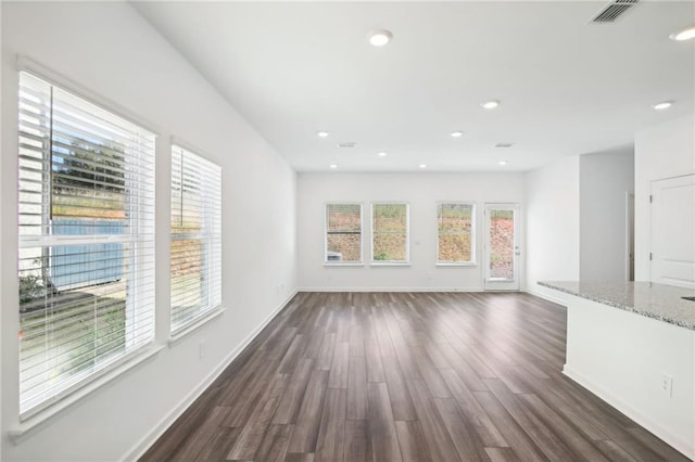 unfurnished living room featuring a wealth of natural light and dark wood-type flooring