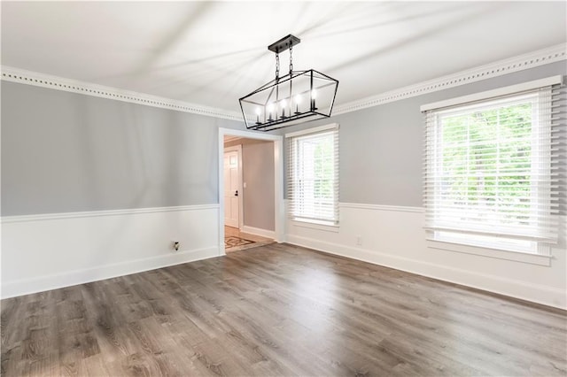 unfurnished dining area with a chandelier, wood finished floors, baseboards, and ornamental molding