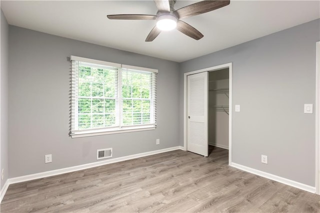 unfurnished bedroom featuring light wood finished floors, baseboards, a closet, and ceiling fan
