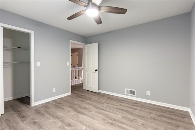 unfurnished bedroom with baseboards, light wood finished floors, and a closet