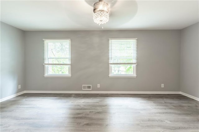 spare room with plenty of natural light, wood finished floors, baseboards, and a ceiling fan