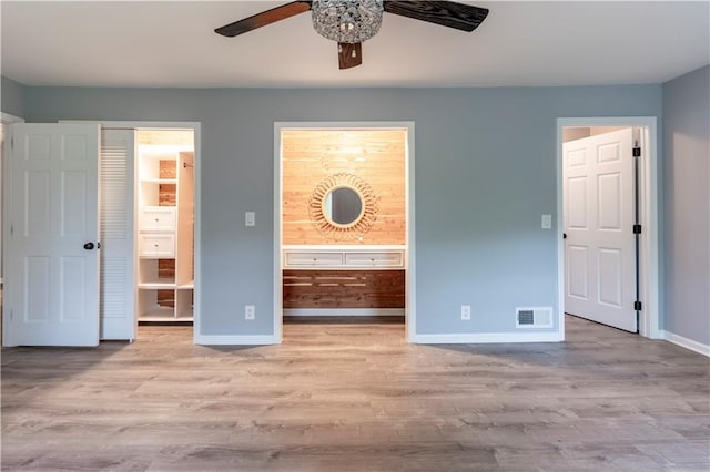 unfurnished bedroom featuring ensuite bath, baseboards, wood finished floors, and ceiling fan