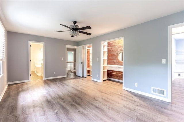 unfurnished bedroom featuring connected bathroom, baseboards, wood finished floors, and a ceiling fan