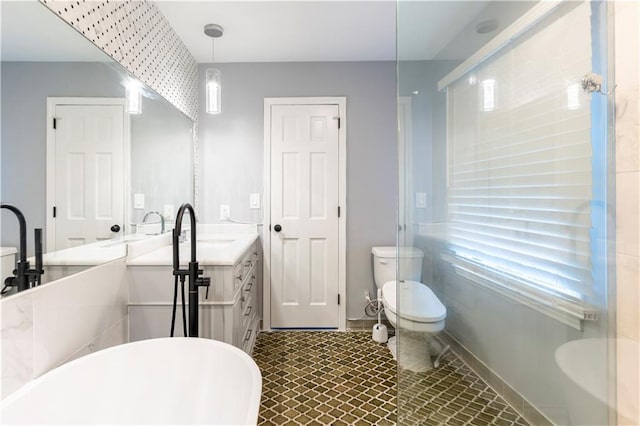 bathroom with a soaking tub, vanity, toilet, and baseboards