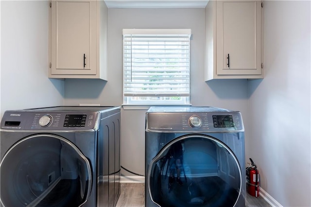 laundry area featuring washing machine and clothes dryer, cabinet space, wood finished floors, and baseboards