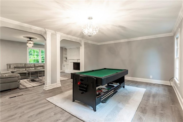 recreation room featuring arched walkways, wood finished floors, a chandelier, baseboards, and crown molding