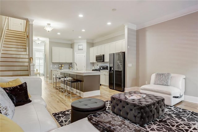 living room with light hardwood / wood-style floors, sink, and crown molding