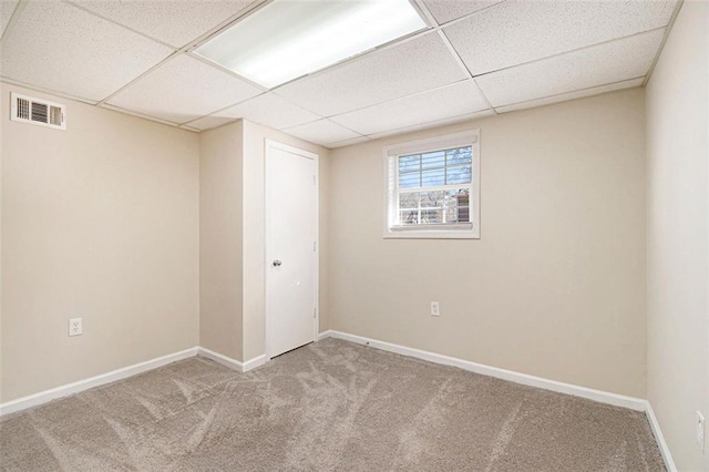 spare room featuring a drop ceiling and light carpet