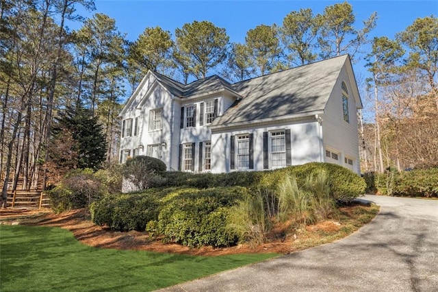 view of property exterior featuring a garage, a yard, and driveway