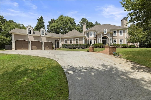 view of front facade with a garage, driveway, a front yard, and stucco siding