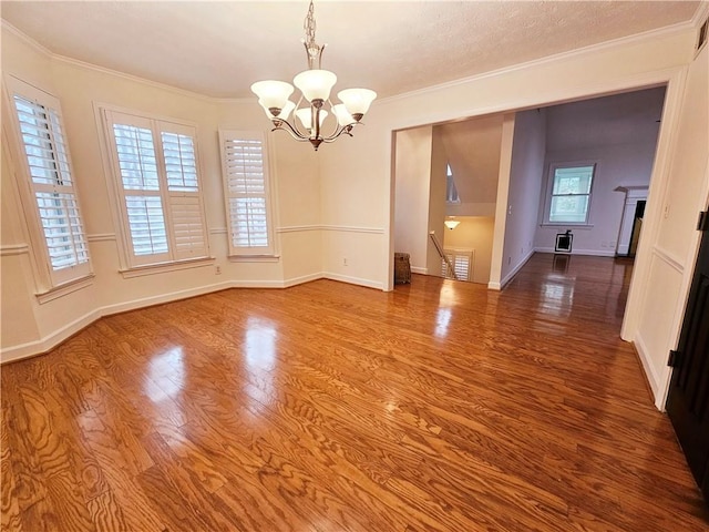 unfurnished dining area with a notable chandelier, wood-type flooring, and ornamental molding