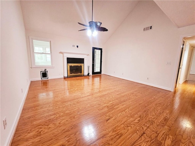 unfurnished living room with visible vents, baseboards, light wood-type flooring, a glass covered fireplace, and a ceiling fan