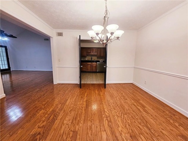 unfurnished dining area with a chandelier, hardwood / wood-style flooring, and crown molding