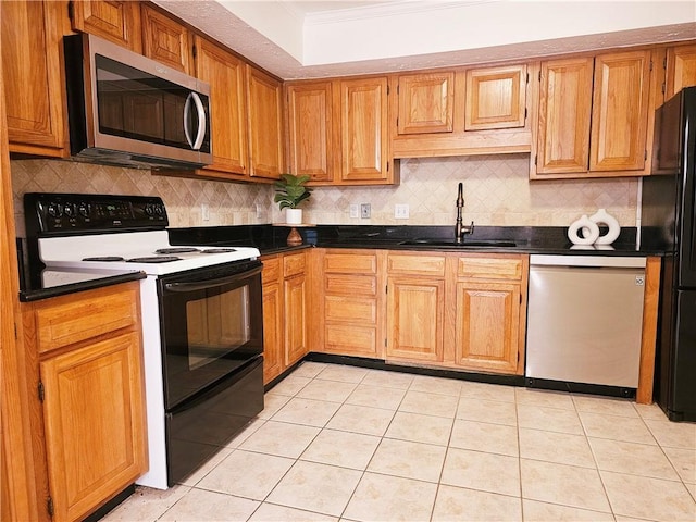 kitchen with dark countertops, crown molding, stainless steel appliances, and a sink