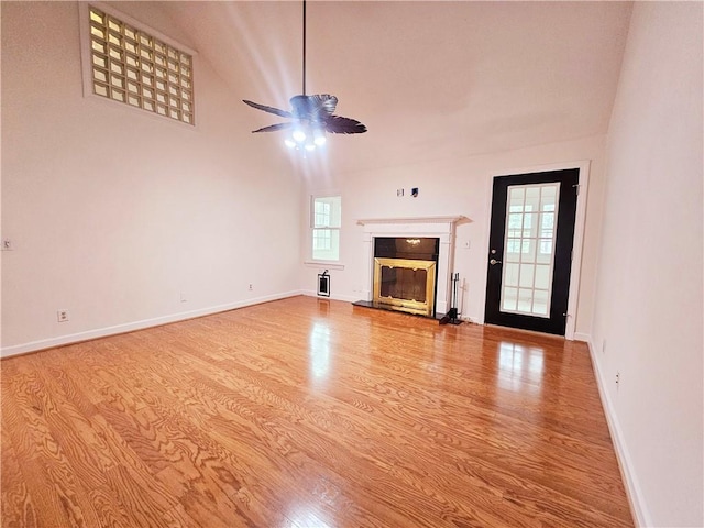 unfurnished living room with a ceiling fan, a glass covered fireplace, wood finished floors, and baseboards