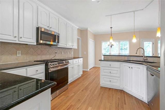 kitchen with hanging light fixtures, appliances with stainless steel finishes, and white cabinets