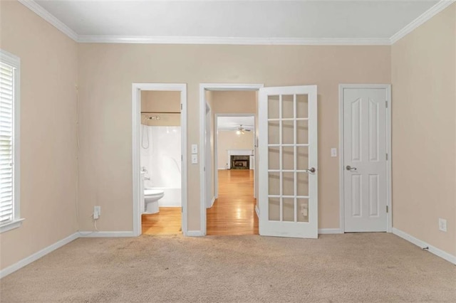 unfurnished bedroom with light colored carpet, ornamental molding, and ensuite bathroom