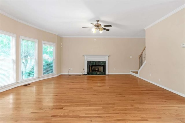 unfurnished living room featuring crown molding, a fireplace, ceiling fan, and light wood-type flooring