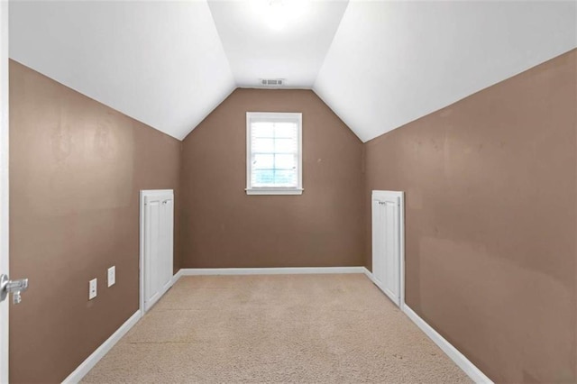 bonus room with lofted ceiling and light carpet