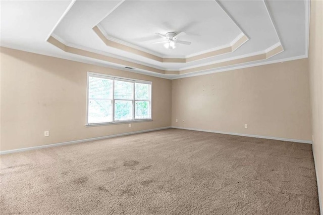 carpeted spare room featuring a raised ceiling, ornamental molding, and ceiling fan