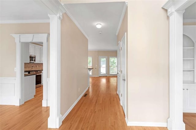 hallway with ornate columns, crown molding, and light wood-type flooring