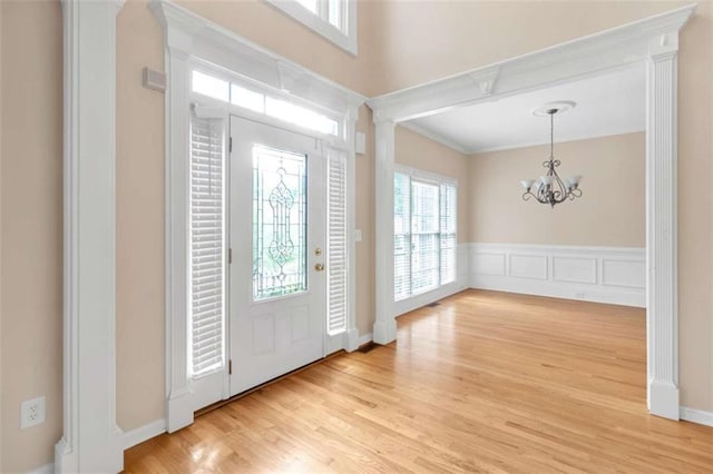 foyer with light hardwood / wood-style flooring, a chandelier, and ornate columns