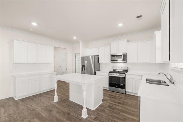 1159 Blue Juniper Cir, Loganville, GA 30052 - kitchen featuring appliances with stainless steel finishes, a sink, backsplash, crown molding, and a kitchen island
