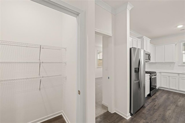 1159 Blue Juniper Cir, Loganville, GA 30052 - kitchen featuring appliances with stainless steel finishes, dark wood-type flooring, white cabinets, baseboards, and ornamental molding