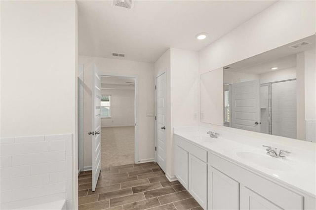 1159 Blue Juniper Cir, Loganville, GA 30052 - bathroom with double vanity, wood finished floors, a shower with shower door, and recessed lighting
