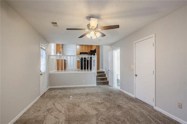 unfurnished living room featuring carpet flooring, ceiling fan, and a textured ceiling