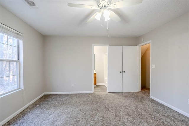 unfurnished bedroom featuring carpet flooring, ensuite bathroom, and ceiling fan