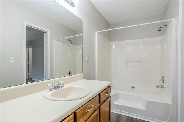 bathroom featuring bathing tub / shower combination, vanity, wood-type flooring, and a textured ceiling