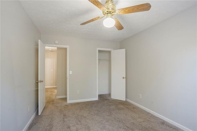 unfurnished bedroom featuring light carpet, a textured ceiling, a closet, and ceiling fan