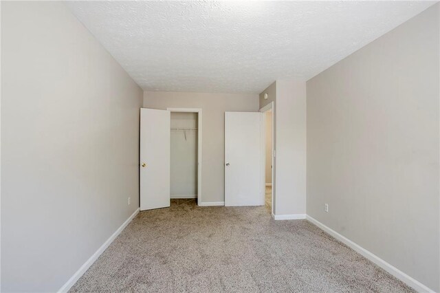 unfurnished bedroom with a closet, light colored carpet, and a textured ceiling