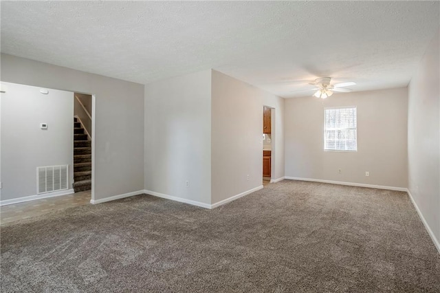 carpeted spare room featuring a textured ceiling and ceiling fan