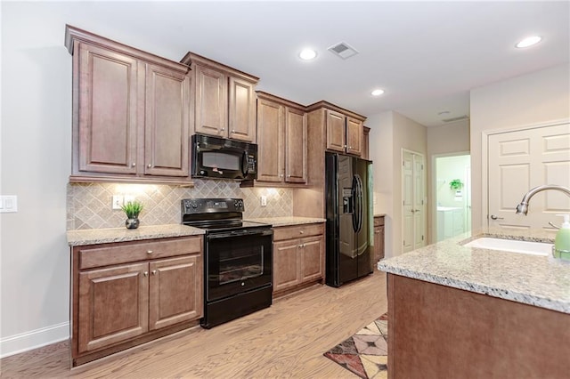 1555 Water Vista Ct Unit 4102, Cumming, GA 30041 - kitchen featuring black appliances, a sink, light wood-style floors, decorative backsplash, and light stone countertops
